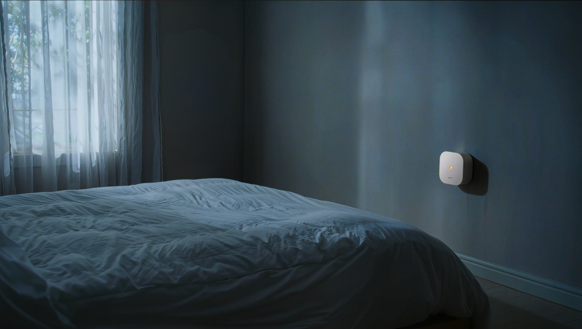 A calm bedroom at night, lit only by the soft amber glow of a small wall sensor.